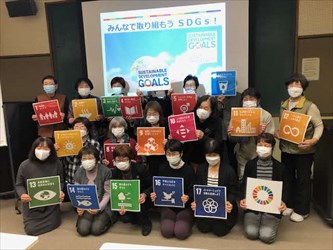 SDGsのロゴを持った人々