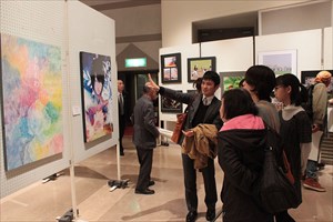 絵画を案内する男性と来客者