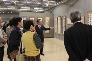 書道作品の前で案内を行う写真